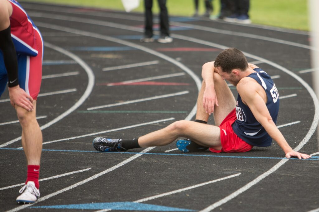 An athlete sitting on a race track, exhausted