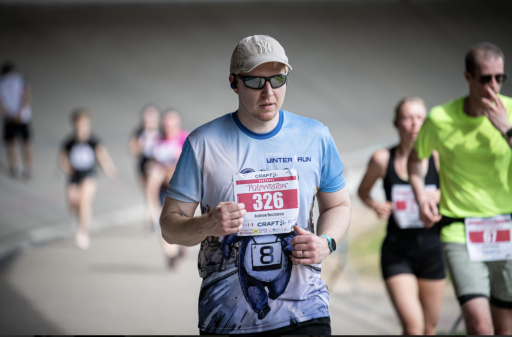 A person running with a race number and blurred competitors in the background